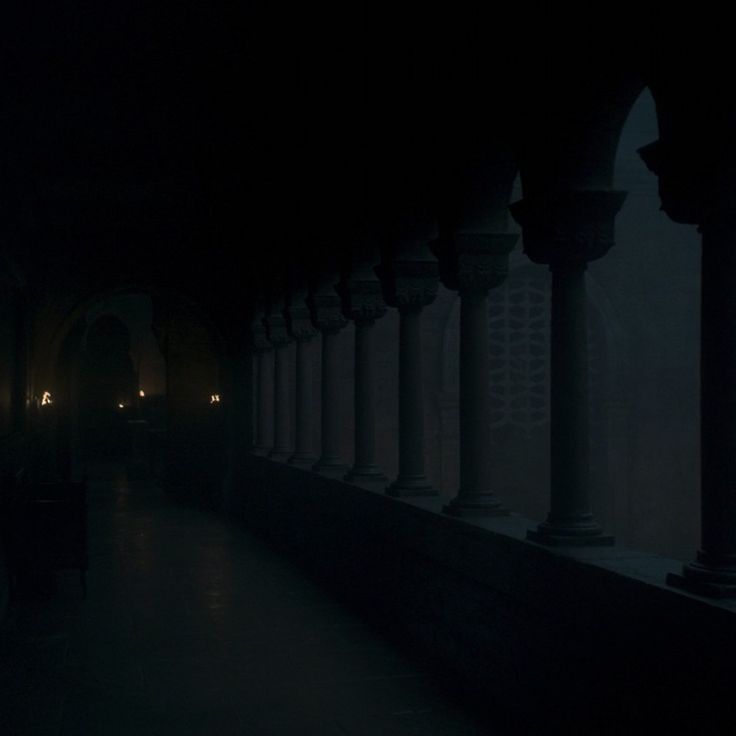 a dark hallway with columns and lights in the distance, on a foggy night