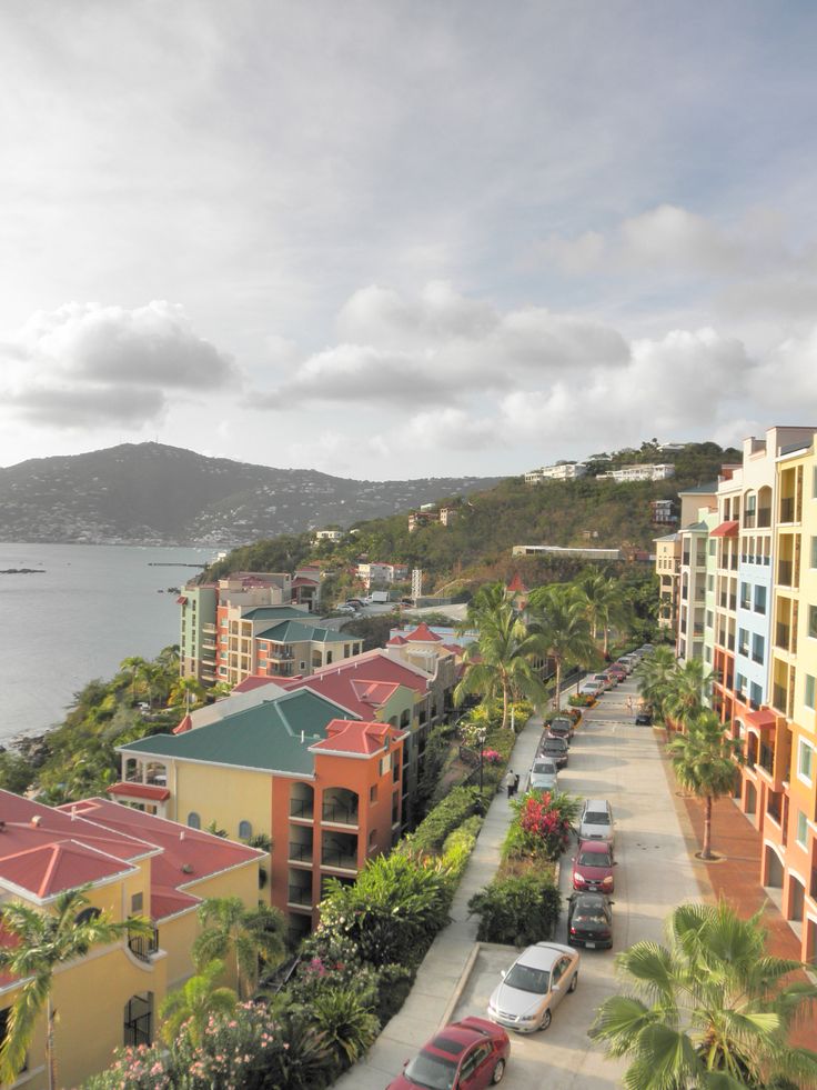 an aerial view of some buildings and cars parked on the street next to the water