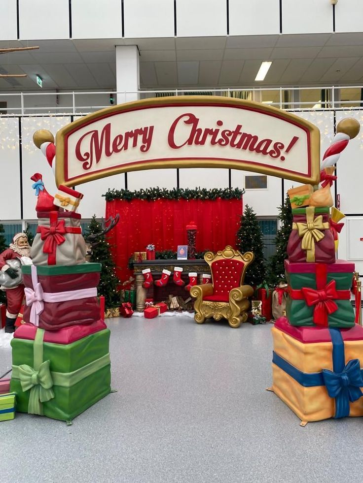 there are many presents stacked on top of each other in front of a merry christmas sign