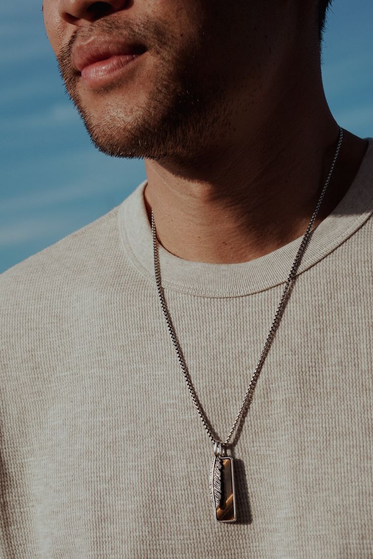 Crafted for the modern spirit, this sterling silver rounded box chain boasts a striking Tiger's Eye tag pendant that represents strength and confidence. Paired with a sleek silver feather charm, this necklace is an everyday piece you'll never take off. Sterling Silver Tiger's Eye 2.5mm Chain Thickness 22"-26" Length (24” pictured) Pendants and Chain sold together Tiger's Eye: Protection, Courage, Balance, Clarity Everyday Pendant Jewelry With Box Chain, Silver Necklaces With Detachable Pendant For Everyday, Silver Necklace With Detachable Pendant For Everyday, Everyday Necklace With Square Pendant And Polished Finish, Everyday Sterling Silver Charm Necklace With Box Chain, Everyday Silver Necklace With Detachable Pendant, Everyday Square Pendant Necklace With Polished Finish, Everyday Jewelry With Initial Pendant On Box Chain, Everyday Jewelry With Box Chain And Initial Pendant