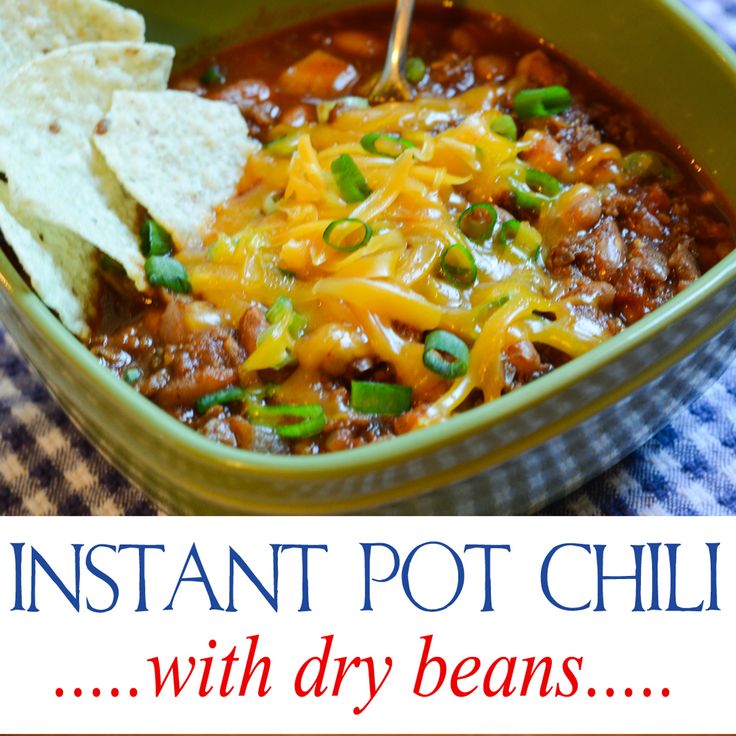 a green bowl filled with chili, cheese and tortilla chips