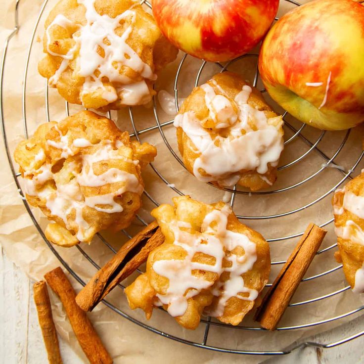 some apples and cinnamon sticks are on a wire rack with white icing next to them