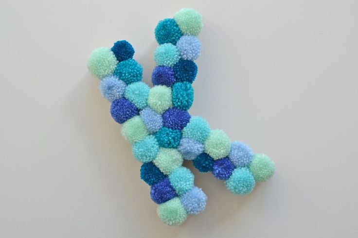 the letter k is made up of multicolored pom - poms on a white surface