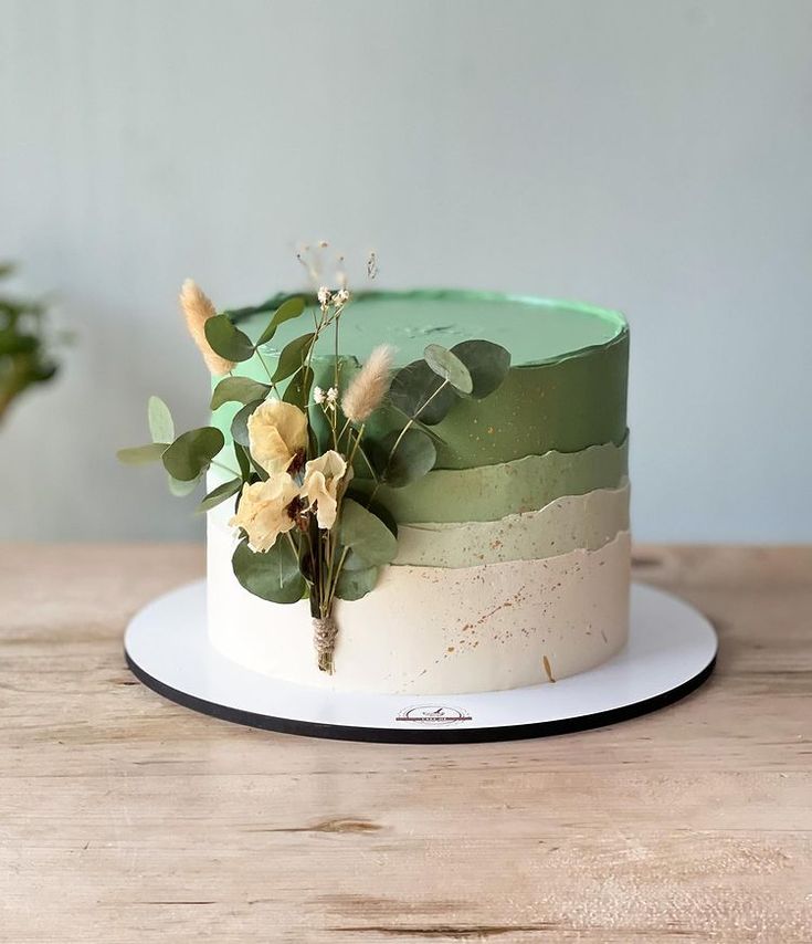 a green and white cake sitting on top of a wooden table next to a potted plant