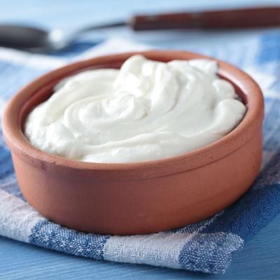 a brown bowl filled with cream sitting on top of a blue and white checkered table cloth