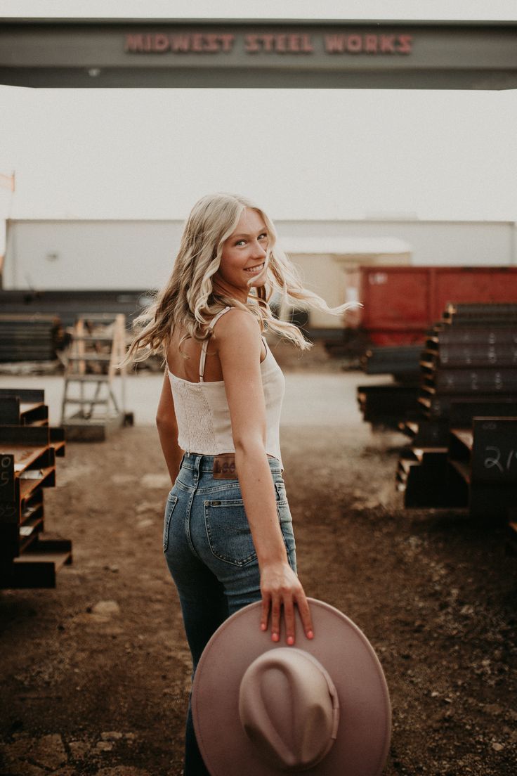 a woman standing in the dirt with her hat on