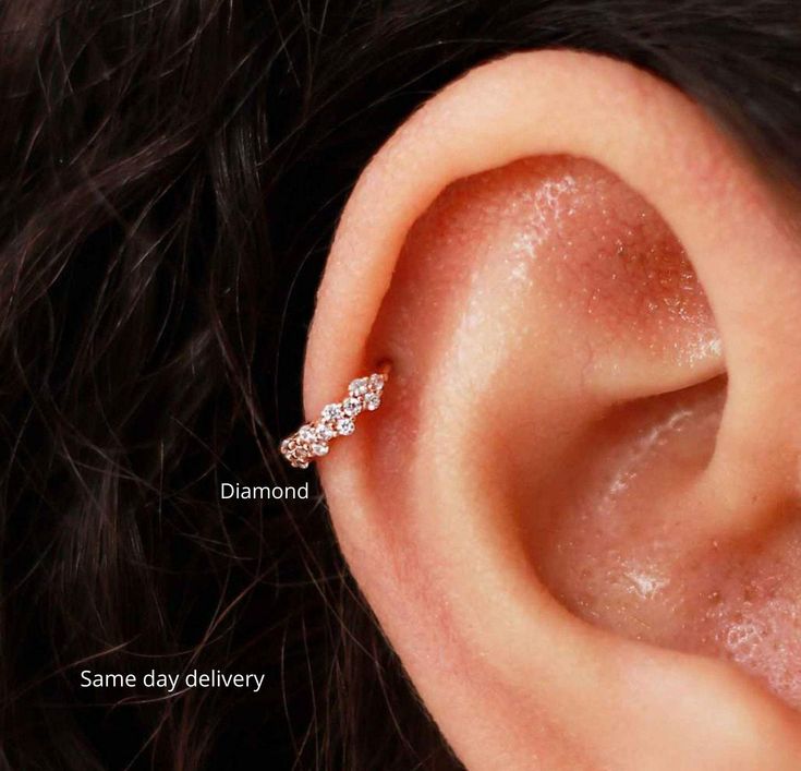 a woman's ear is shown with three small diamonds on the end of it