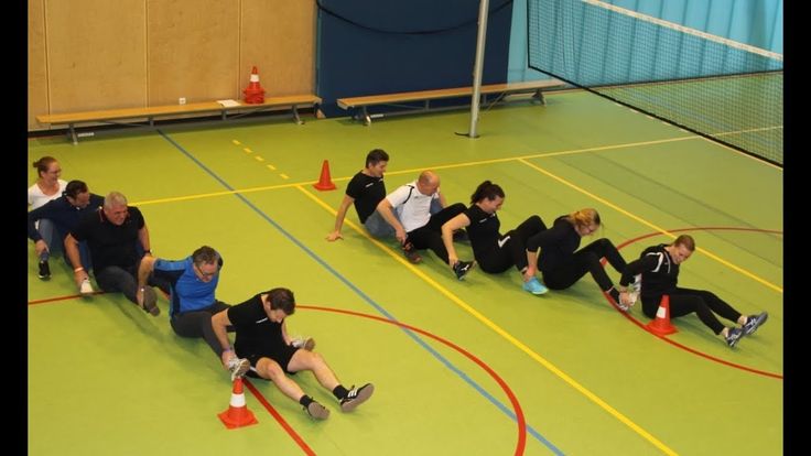 a group of people sitting on top of a green floor next to each other in front of an orange cone