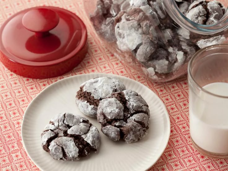 some cookies are on a plate next to a glass of milk and a red container