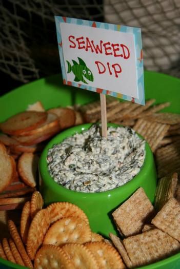 a green plate topped with crackers and a sign that reads, seaweed dip