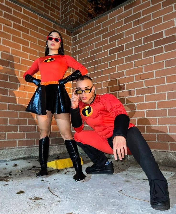 two people dressed in costumes posing for a photo next to a brick wall and yellow fire hydrant