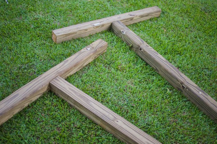 four pieces of wood laying in the grass on top of each other with nails sticking out of them