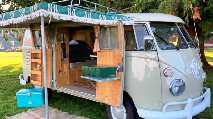 an old vw bus converted into a camper with its door open and the roof up