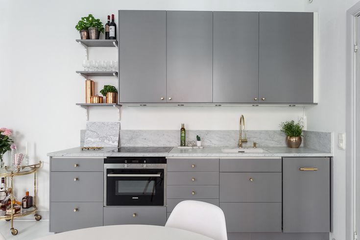 a kitchen with gray cabinets and marble counter tops, white dining room table and chairs