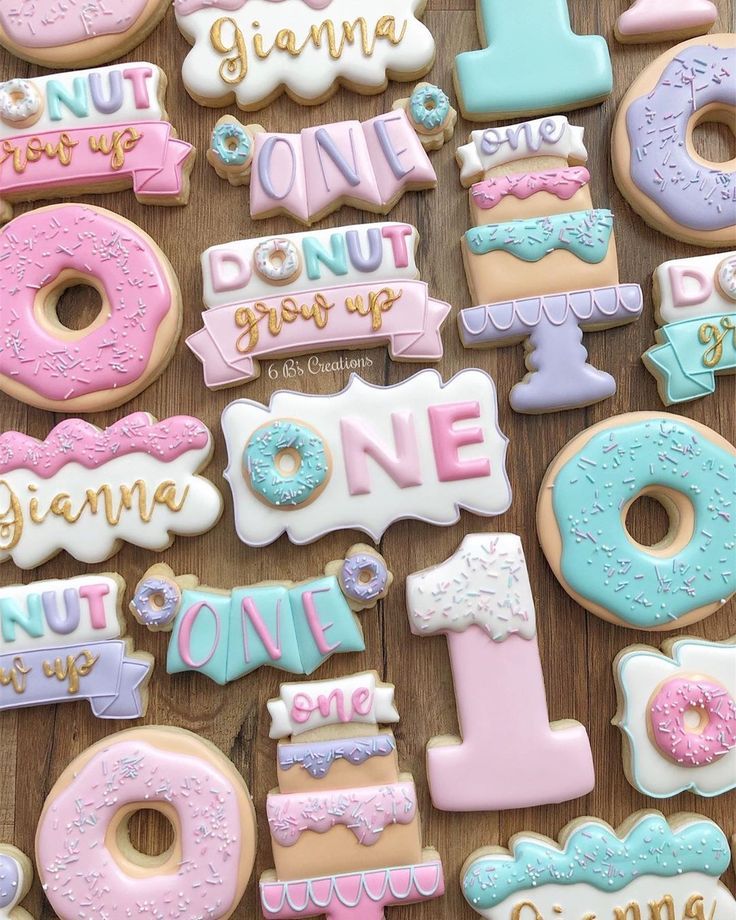 decorated cookies are arranged on a table with the words donuts grow up and one is 1