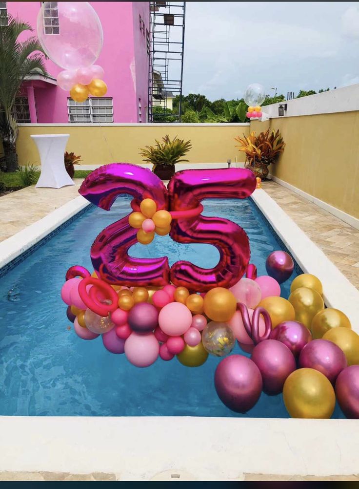 a pool with balloons floating in it and the number twenty five surrounded by other decorations