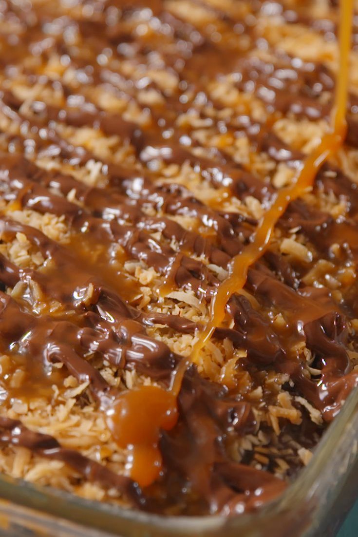 a casserole dish filled with rice and chocolate sauce being drizzled on top