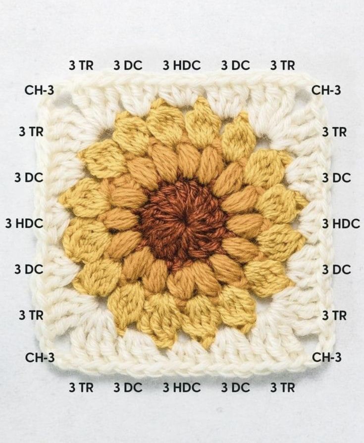 a crocheted square with a yellow and brown flower on it's center