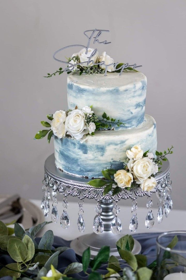 a blue and white wedding cake with flowers on top