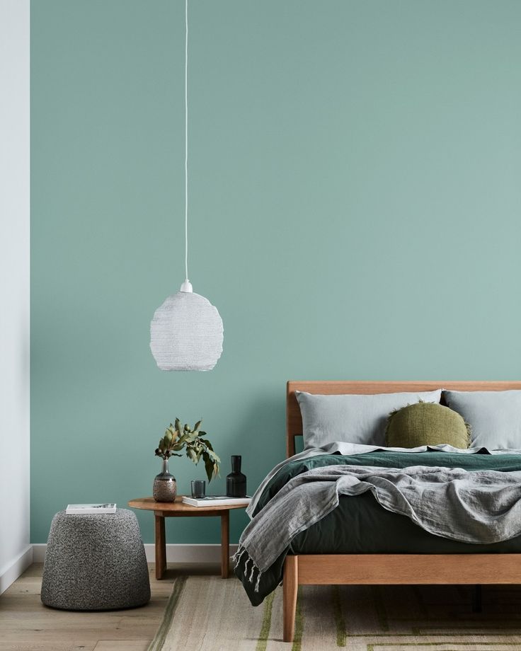 a bedroom painted in teal and white with a bed that has two pillows on it