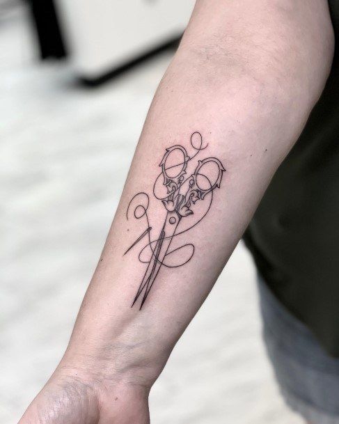 a person with a tattoo on their arm holding a pair of scissors in one hand