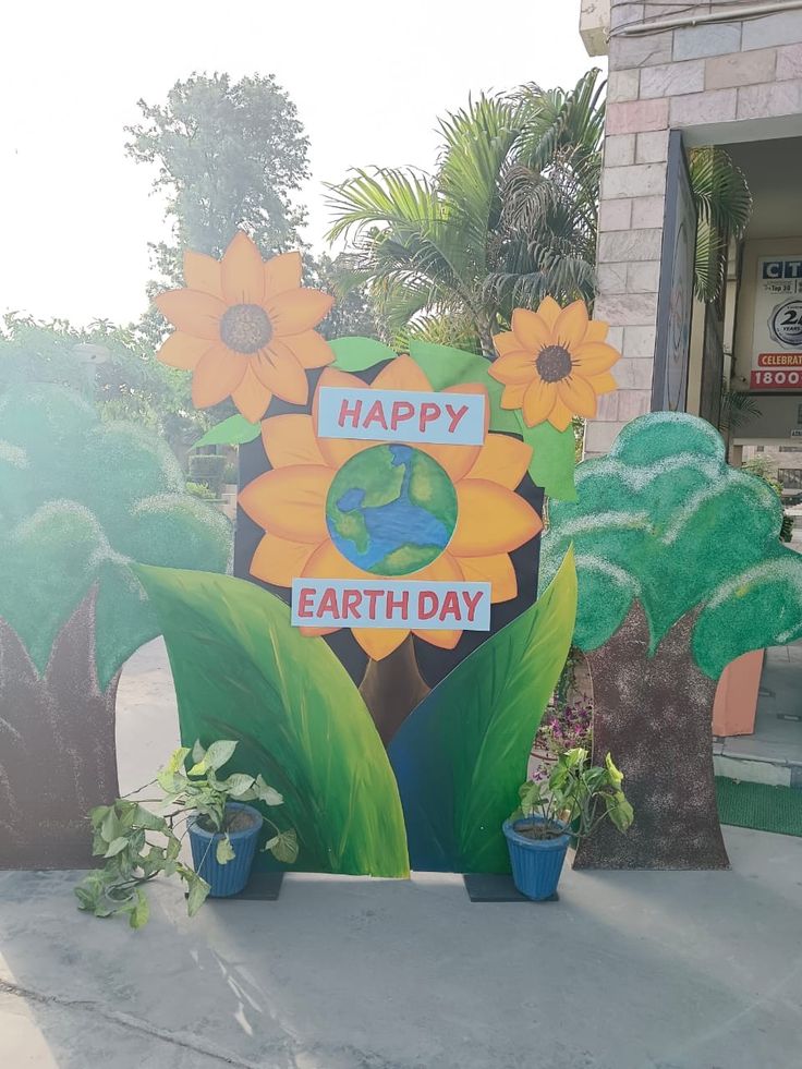 there is a sign that says happy earth day with flowers in front of the building