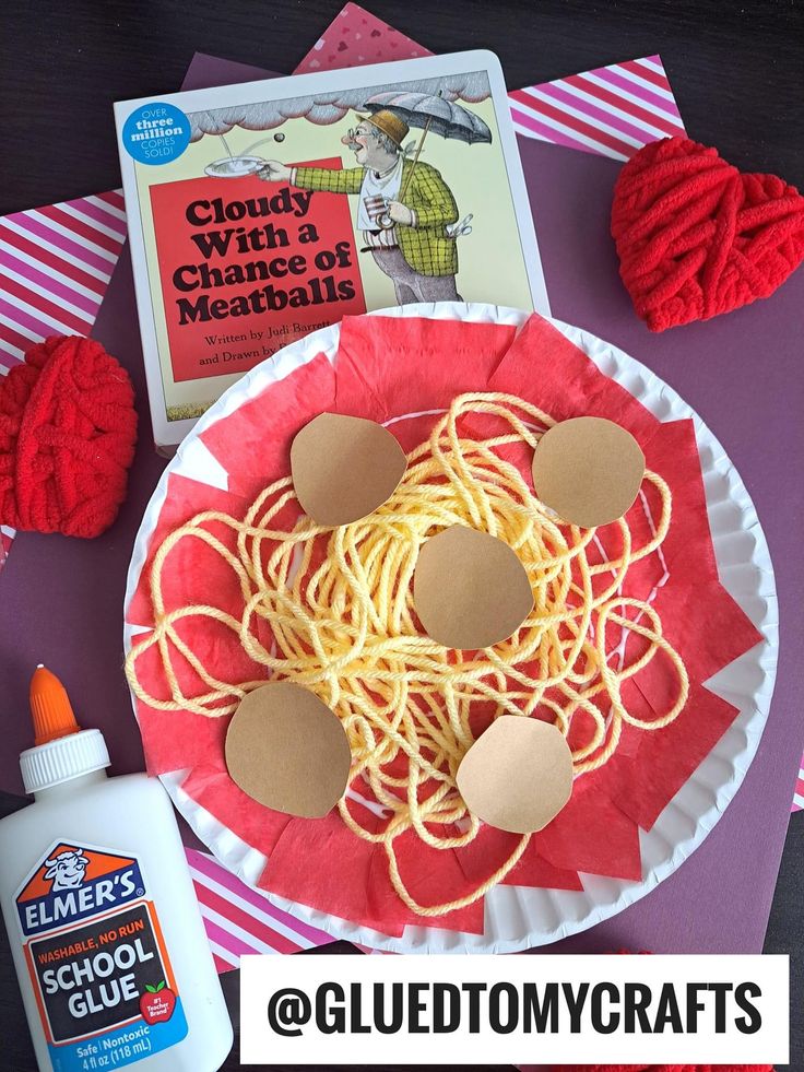 a paper plate with spaghetti and glue on it, next to a copy of the book cloudy with a chance of meowballs