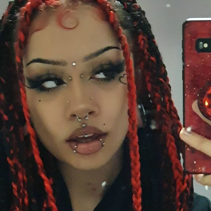 a woman with red dreadlocks taking a selfie in front of a mirror