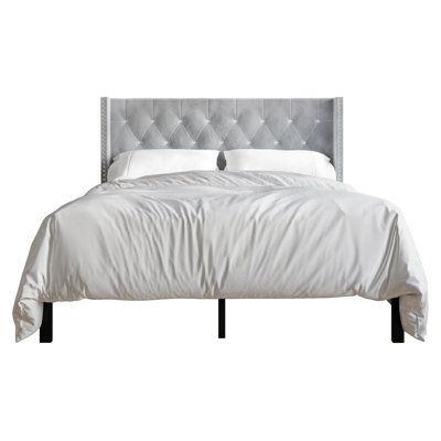 the bed is made up with white sheets and silver headboard, along with two pillows