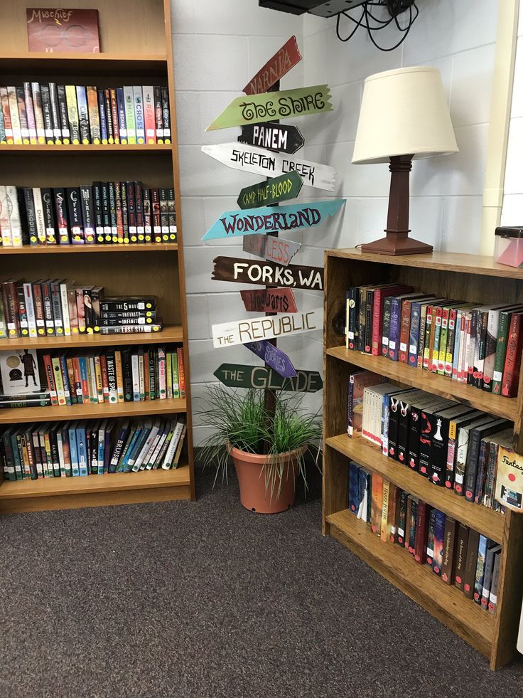 there are many bookshelves in the library with signs on each shelf and a lamp next to them