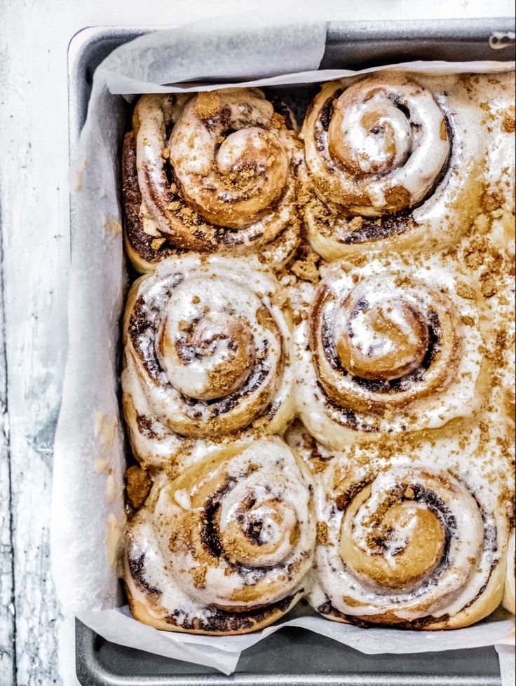 cinnamon rolls in a baking pan with powdered sugar on top