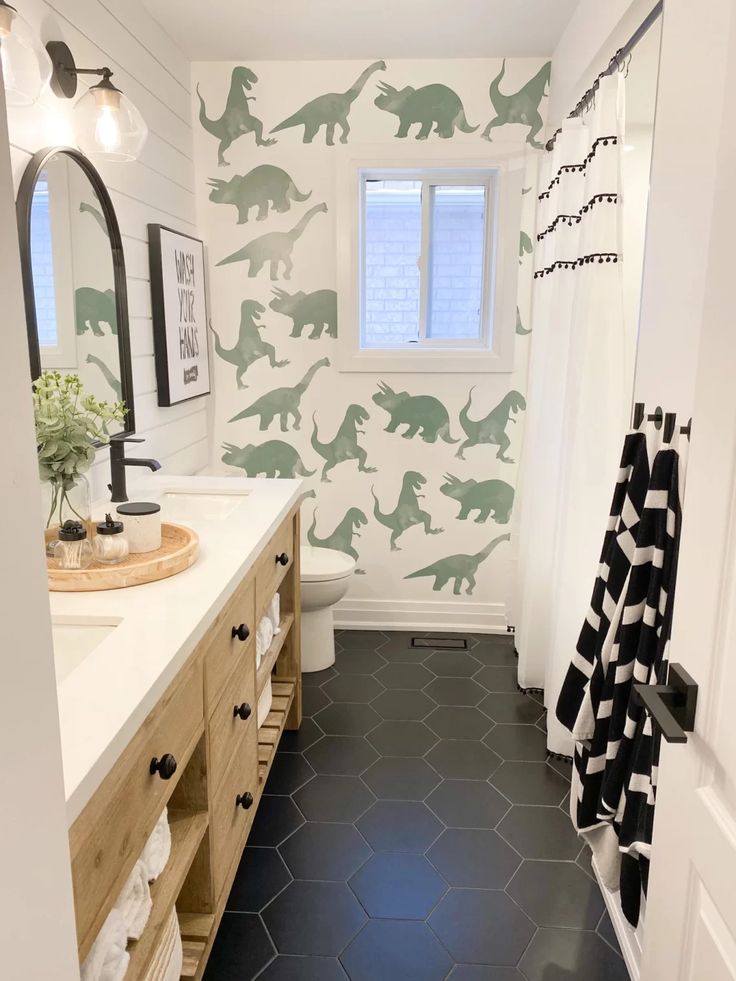 a bathroom decorated with dinosaur wallpaper and black tile flooring, along with white walls