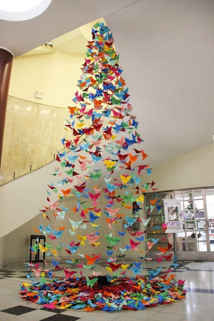 a very large christmas tree made out of origami paper cranes in a lobby