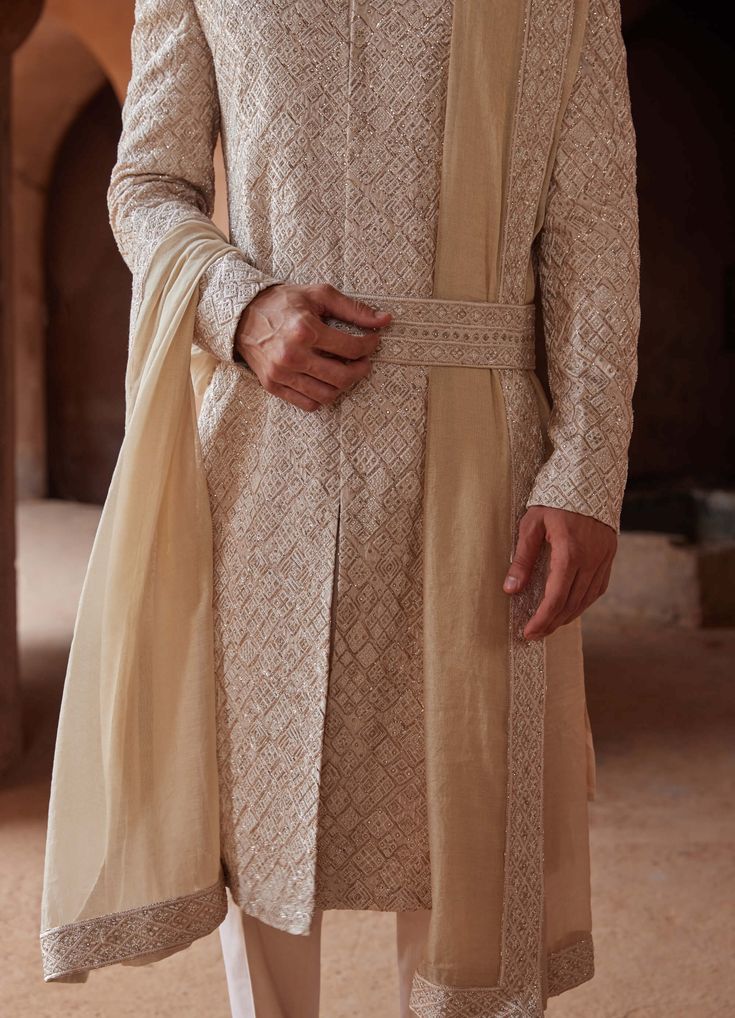 Editor's Note Step into elegance with our mushroom raw silk sherwani, adorned with intricate tonal resham embroidery and delicate rose gold pitta work all over. Paired with a monga tussar kurta and cotton lycra trousers, this ensemble effortlessly blends modern aesthetics with classic charm. Perfect for showcasing a refined and sophisticated look on your special occasion. Note: Stole and belt are for styling purposes only. Fabric: Raw silk, monga tussar and cotton Color: Beige Components: Sherwa Raw Silk Embroidery, Raw Silk Kurta, Embroidered Sherwani, Blouse Yoke, Resham Embroidery, Resham Work, Silk Kurta, Indian Groom, Mens Luxury Fashion