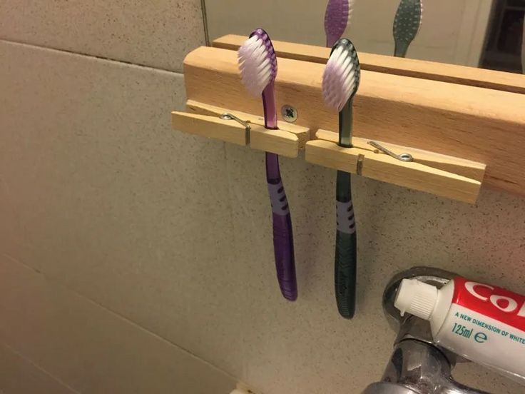 three toothbrushes are hanging on a wooden rack