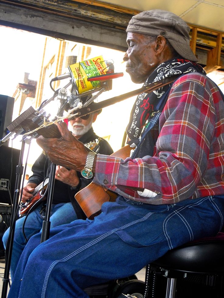 an old man sitting in a chair with a guitar and microphone next to him on the stage