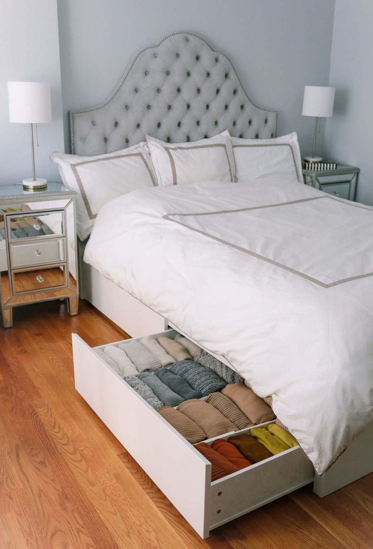 a bed with two drawers underneath it on the floor next to a night stand and lamp