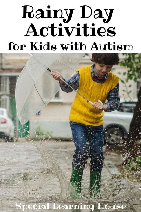 a little boy playing in the rain with an umbrella