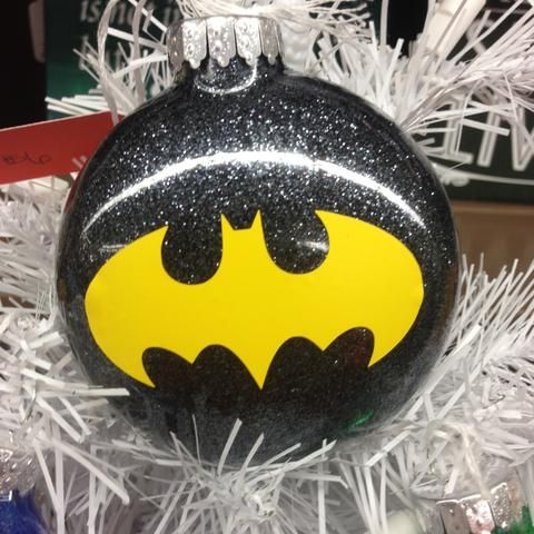 a batman ornament on top of a christmas tree with tinsel and glitter