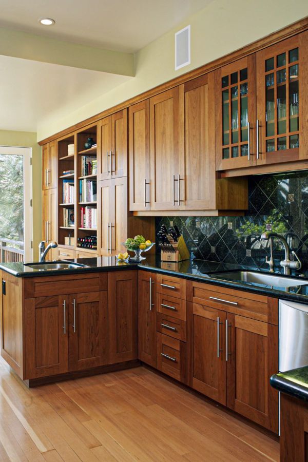 a kitchen with wooden cabinets and black counter tops, along with a dining room table