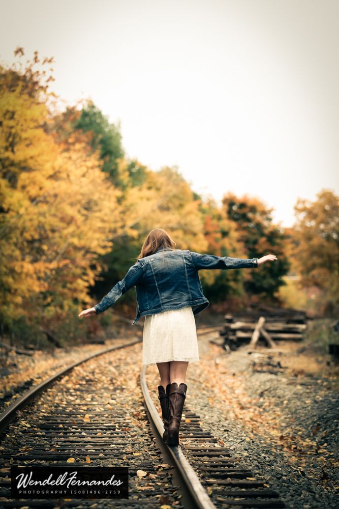 a woman walking on train tracks with her arms outstretched