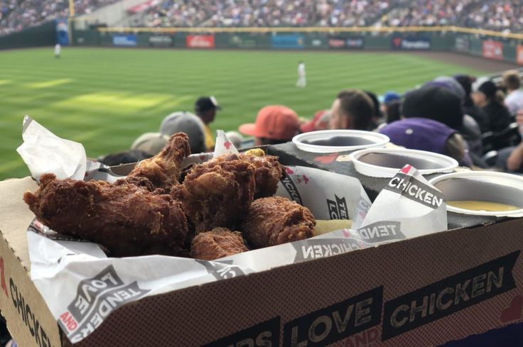 a box filled with fried chicken sitting on top of a baseball field covered in people