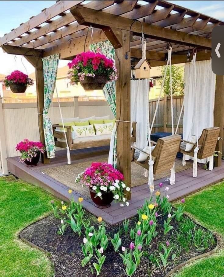 a wooden gazebo sitting on top of a lush green field next to a flower garden