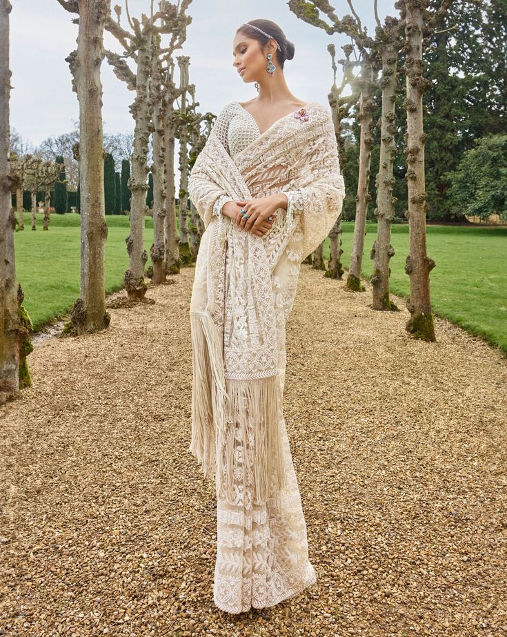 This saree features intricate embroidery in thread, pearl and sequin in a linear pattern. The saree has an exaggerated fringe. The full sleeves blouse has a plunging neckline with tassel details. This comes with an optional sheer net veil with soft fringe.From Seema Gujral's A Royal Affair collection. DELIVERY TIMEPlease allow 8-12 weeks for your outfit to arrive. FABRIC DETAILSNet Professional cleaning only. Bohemian Pre-draped Saree With Unstitched Blouse For Wedding, V-neck Chikankari Embroidery Traditional Wear For Wedding, V-neck Traditional Wear With Chikankari Embroidery For Wedding, Bohemian Pre-draped Saree With Sheer Dupatta For Designer Wear, Bohemian Pre-draped Saree With Dupatta For Wedding, Bohemian Wedding Pre-draped Saree With Dupatta, Bohemian Blouse Piece For Diwali Reception, Bohemian Pre-draped Saree For Wedding And Festive Occasions, Designer Lace Blouse Piece