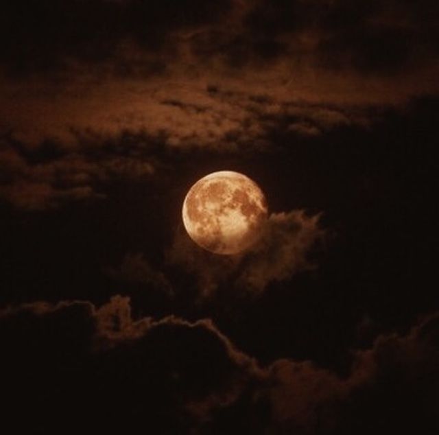 the full moon shines brightly in the night sky above clouds and dark, cloudy skies