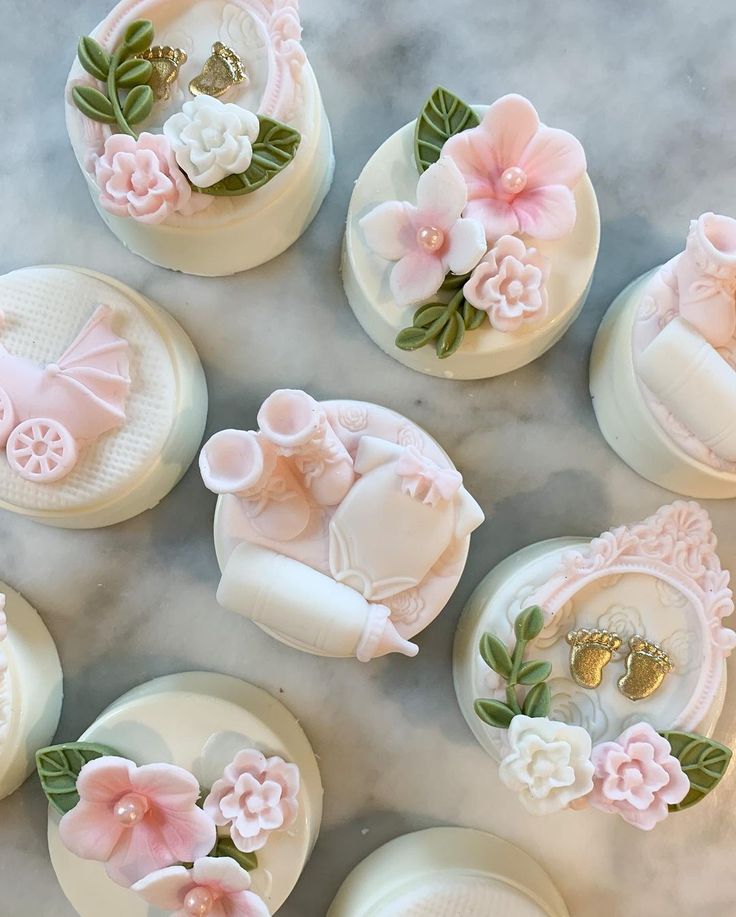 several pink and white buttons with flowers on them sitting on a marble counter top next to each other