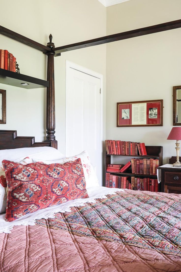 a bedroom with a bed, bookshelf and mirror on the wall above it