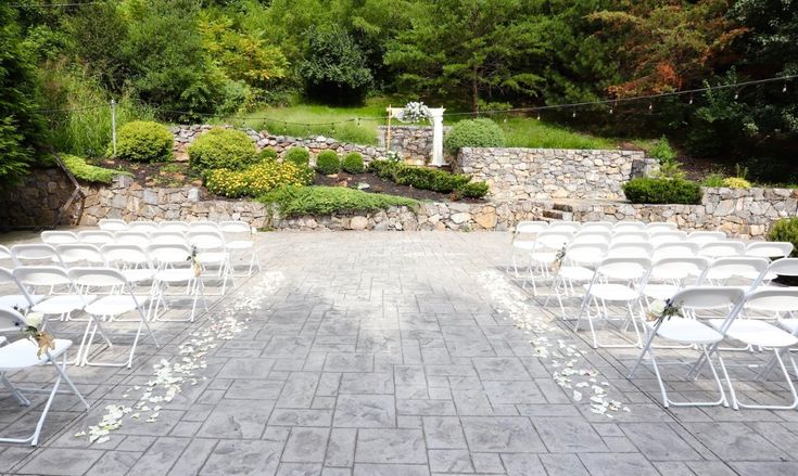 an outdoor ceremony set up with white folding chairs