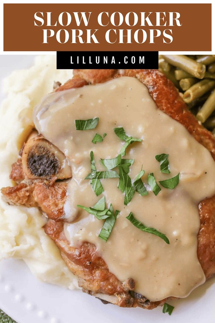 a white plate topped with meat covered in gravy next to mashed potatoes and green beans