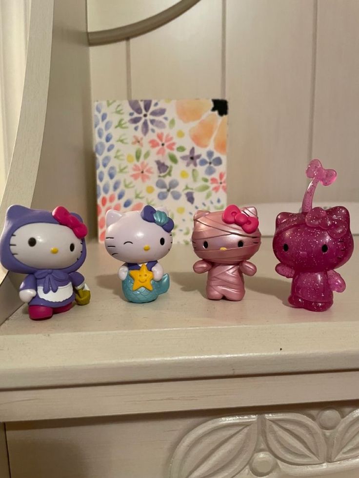 three hello kitty figurines sitting on top of a white table next to a mirror